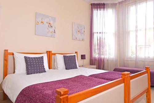 a bedroom with a large bed with a purple blanket at Cavendish apartment - central and spacious in Eastbourne