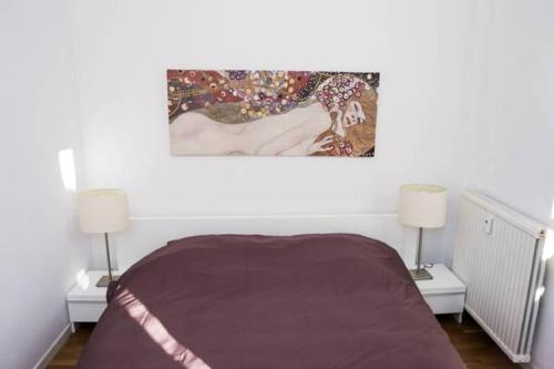 - une chambre avec un lit avec deux lampes et un tableau mural dans l'établissement Appartement Cannes rue Marceau, à Cannes