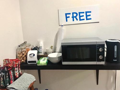a microwave on a shelf with a free sign on it at Uh Hostel in Bangsaen