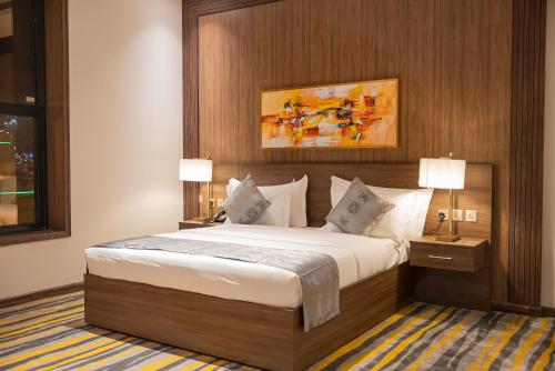 a bedroom with a large bed and two lamps at DiYar Home Hotel in Baljurashi