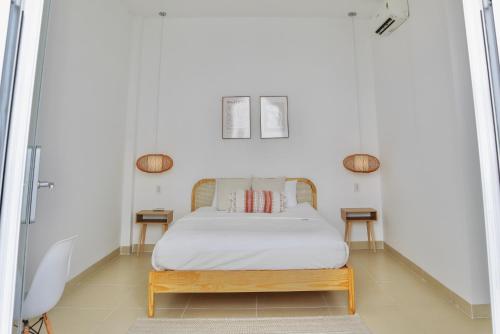 a bed in a white room with two tables at LASAOMA HOMESTAY in Can Tho