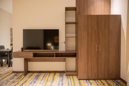 a large wooden entertainment center with a television on it at DiYar Home Hotel in Baljurashi