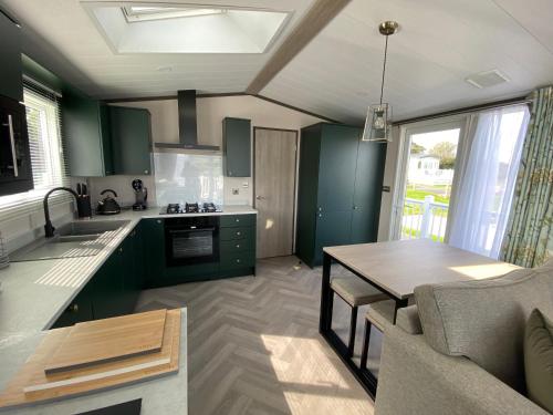 a kitchen with green cabinets and a table in a room at Riverwood Lodge in Porth