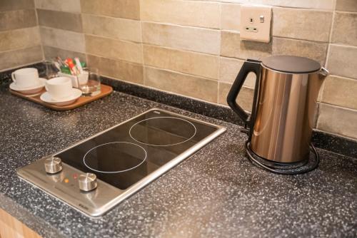 a stove top with a coffee pot on a counter at DiYar Home Hotel in Baljurashi