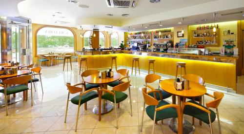 a restaurant with tables and chairs and a yellow bar at Hotel Florida in Arteixo