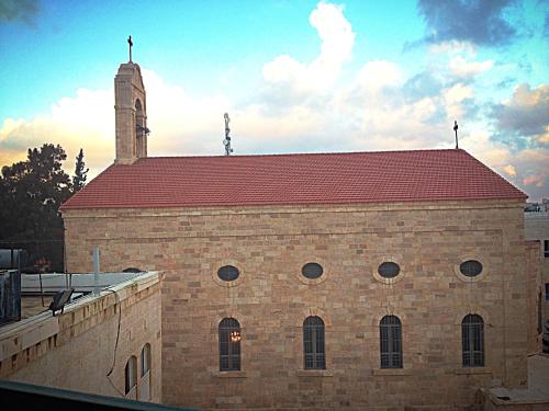 a brick building with a clock tower on top of it at Pilgrim's Guest House in Madaba