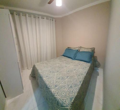 a bedroom with a bed with blue pillows on it at SOL & MAR I com VARANDA - 1 dormitório - Canto do FORTE - 300 m da Praia e 20m da Avenida dos Barzinhos - ESTACIONAMENTO gratuito e WI Fi 300mbytes com TV a cabo - ap113 in Praia Grande