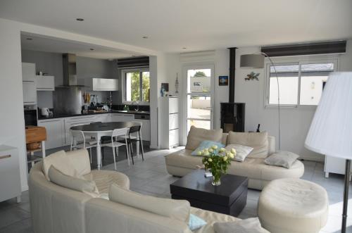 Il comprend un salon avec un mobilier blanc et une cuisine. dans l'établissement La Magnifique Villa à 500m de la plage, à Plozévet