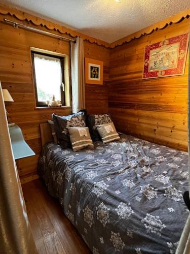 une chambre avec un lit dans une cabane en bois dans l'établissement Appartement la Clusaz avec terrasse sur les pistes de ski, à Manigod