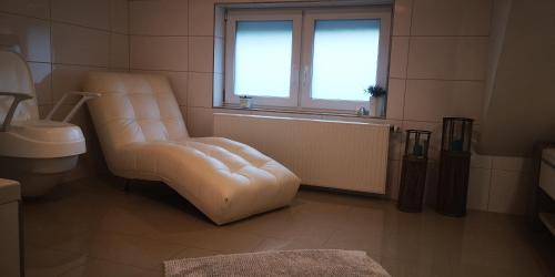 a living room with a white chair and a window at SLEEP WELL Apartments, FEWO Falkenburg in Detmold