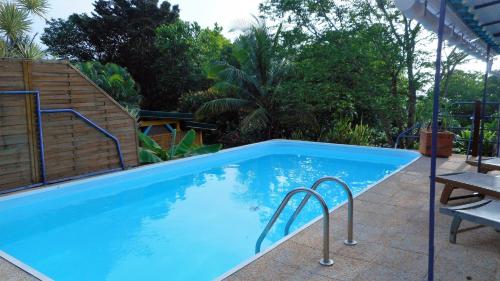 una grande piscina blu con tavolo e sedie di GWAN THAZAR en Guadeloupe a Bouillante