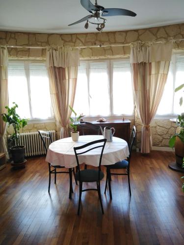 une salle à manger avec une table, des chaises et des fenêtres dans l'établissement Petite chambre meublée au cœur de ville - chez l'habitant, au Creusot