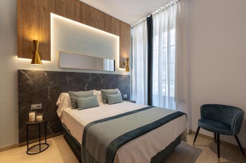 a bedroom with a large bed and a chair at BiBo Suites San Agustín in Granada