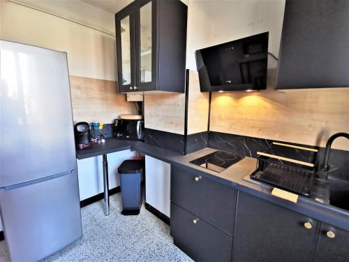 - une cuisine avec des armoires noires et un réfrigérateur dans l'établissement Appartement tout confort refait à neuf, à Moulins