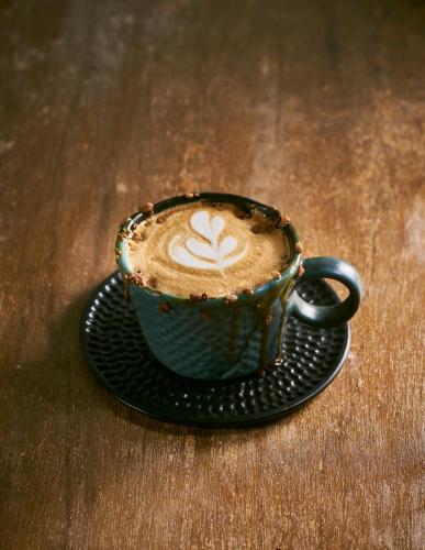 a cup of coffee on a plate on a table at Goose Living in Bangkok