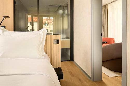a bedroom with a white bed and a chair at Hotel Ambasador in Split