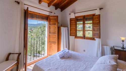 ein Schlafzimmer mit einem Bett und einem großen Fenster in der Unterkunft Casa Guajar Monda by Ruralidays in Monda