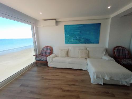 ein Wohnzimmer mit einem weißen Sofa und Strandblick in der Unterkunft Primera línea playa Puerto Santa María vistas infinitas Limpieza excepcional PARKING in El Puerto de Santa María