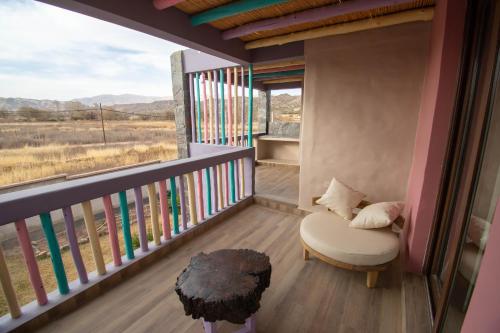 a room with a balcony with a chair and a window at Tikay Humahuaca Refugio de Tierras in Humahuaca