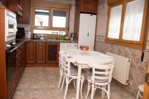 cocina con mesa blanca y sillas blancas en La casona de isa, en Palazuelos de Eresma