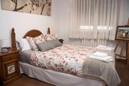 una camera da letto con un letto con copriletto floreale di La casona de isa a Palazuelos de Eresma