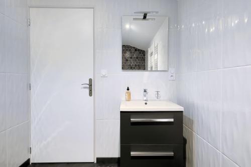 ein weißes Badezimmer mit einem Waschbecken und einem Spiegel in der Unterkunft Advitamrelais in La Rouquette