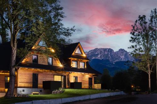 a house with mountains in the background at night at Villa T Apartments & SPA in Zakopane