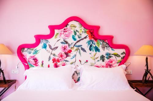 a pink bedroom with a white bed with a floral headboard at Boutique Hotel Don Alfonso 1890 in SantʼAgata sui Due Golfi