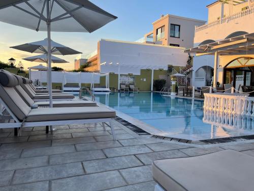 a pool with chairs and umbrellas on a resort at Fedra Mare in Agios Stefanos