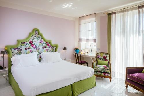 - une chambre avec un grand lit et une chaise dans l'établissement Boutique Hotel Don Alfonso 1890, à SantʼAgata sui Due Golfi