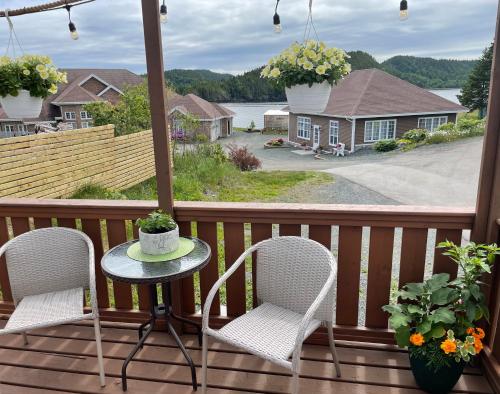 a table and chairs on a porch with a view of the water at Squid Cove Cottage in Pilleyʼs Island