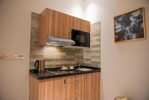 a small kitchen with a sink and a microwave at DiYar Home Hotel in Baljurashi