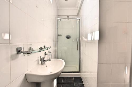 a white bathroom with a sink and a shower at Engine House apartment - a Unique Holiday Home for 2 in Marazion
