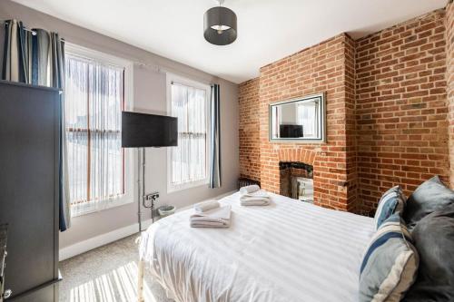 a person laying on a bed in a bedroom with a brick wall at Villa Otto - Norfolk Holiday Properties in Cromer