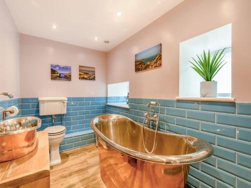 baño con bañera de cobre y azulejos azules en Point House en Milford Haven