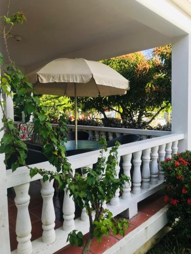 a white railing with an umbrella on a porch at HCEAS villa is 5 min fr. airport & to the beaches in Bon Accord