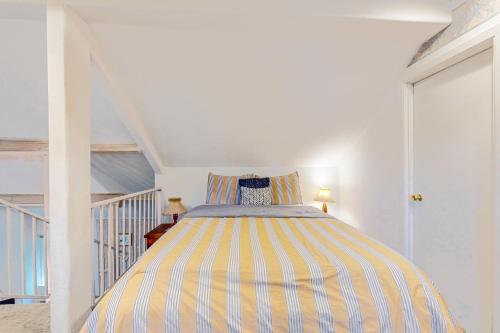 a striped bed in a white room with a staircase at Marcia's Mercer Lake Chateau in Florence