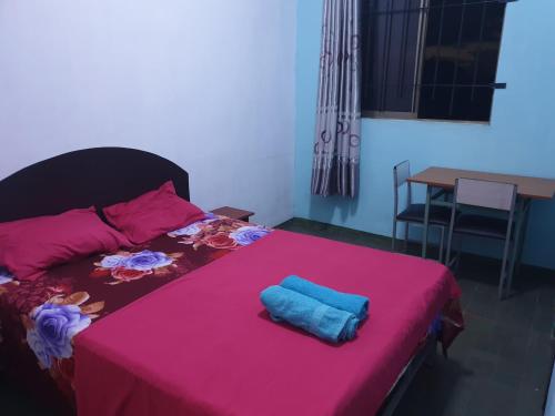 ein Bett mit einer rosa Decke und einem blauen Handtuch darauf in der Unterkunft Villa Pointe Aux Piments in Pamplemousses Village