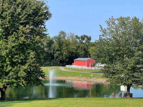 a pond with a red barn and a fountain at Hershey Farm Resort in Ronks