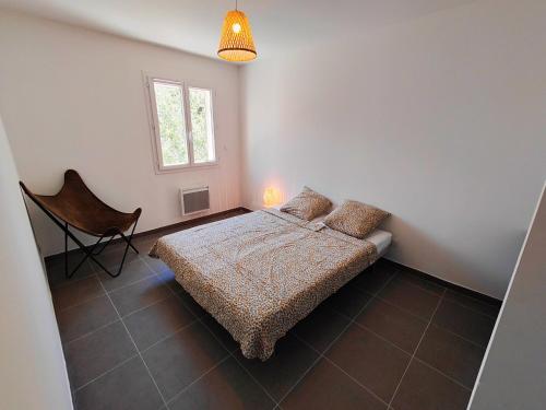 a bedroom with a bed and a chair and a window at Villa Vias Plage neuve in Vias