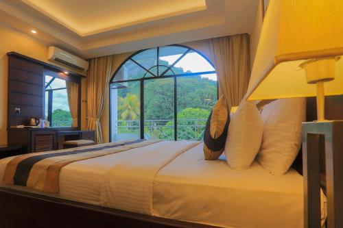 a bedroom with a large bed with a large window at Kandyan Reach Hotel in Kurunegala