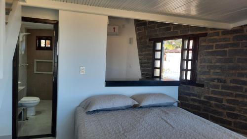 a bedroom with a bed and a brick wall at Bangalô Aconchegante de Frente para o Mar in Prado