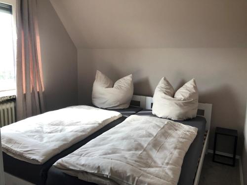 2 Betten mit weißer Bettwäsche und Kissen in einem Zimmer in der Unterkunft Wohnung mit Fernblick und Parkplatz in Jübek