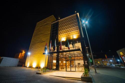 un bâtiment avec drapeaux devant lui la nuit dans l'établissement DiYar Home Hotel, à Baljurashi