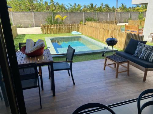 une terrasse avec une table, des chaises et une piscine dans l'établissement Oka Milagres Residence 06, à São Miguel dos Milagres