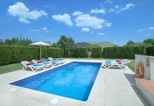 a swimming pool with chairs and an umbrella at Owl Booking Villa Tofol - Ideal For Family and Friends in Pollença