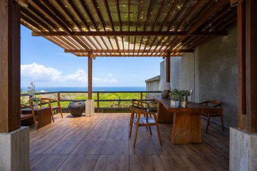 a patio with a table and chairs and a view of the ocean at Moritz Palm Villa in Uluwatu
