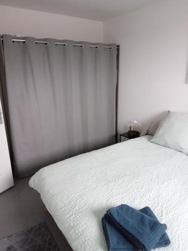 a white bed with a blue towel on it at Roubaix près Lille, un cocon en plein centre in Roubaix