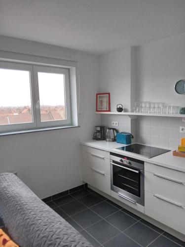 uma cozinha com armários brancos e um forno com placa de fogão em Roubaix près Lille, un cocon en plein centre em Roubaix