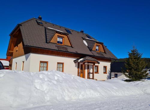 a house with a pile of snow in front of it at Chata Terezka in Kvilda